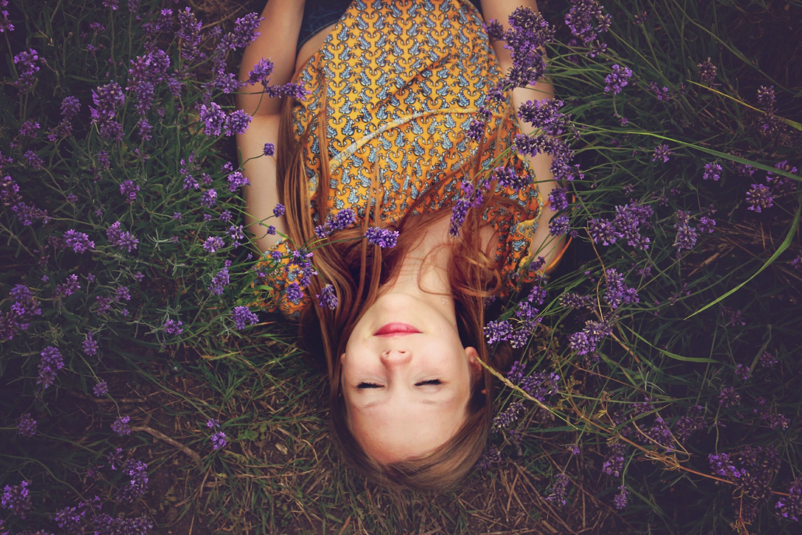 Femme allongée yeux fermés dans un champs de fleurs